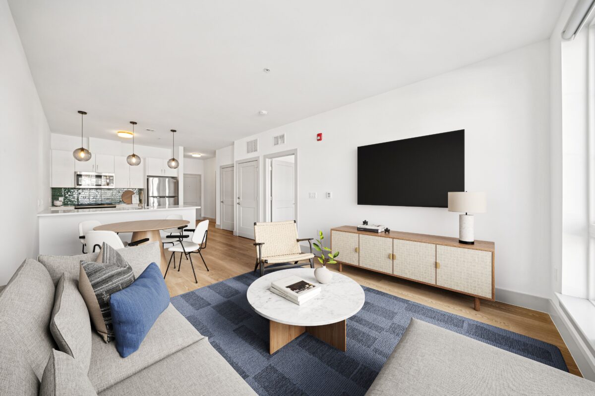 Open-concept living room with a kitchen, dining area, and hardwood floors.