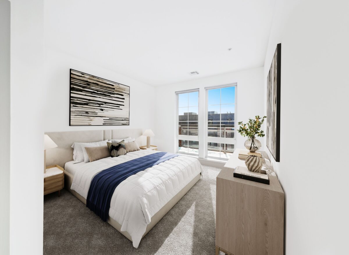 A modern bedroom with a large bed, two windows, and a light wood dresser with decor.