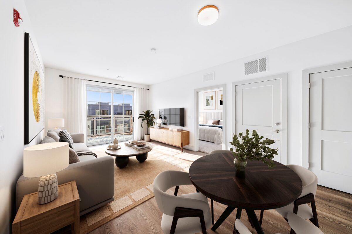 Open-concept living and dining area with wood-style flooring, a balcony, and a view into a bedroom.
