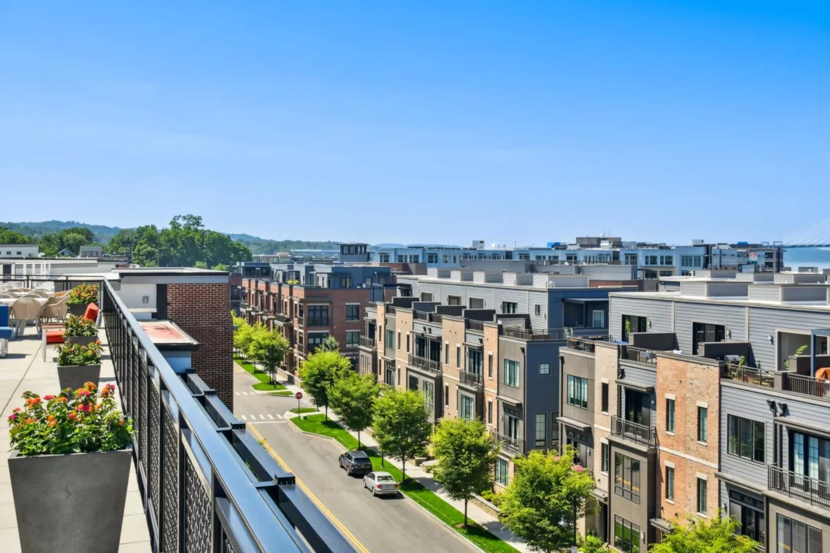 Aerial view of a row of brick apartment buildings with a rooftop patio in the foreground.